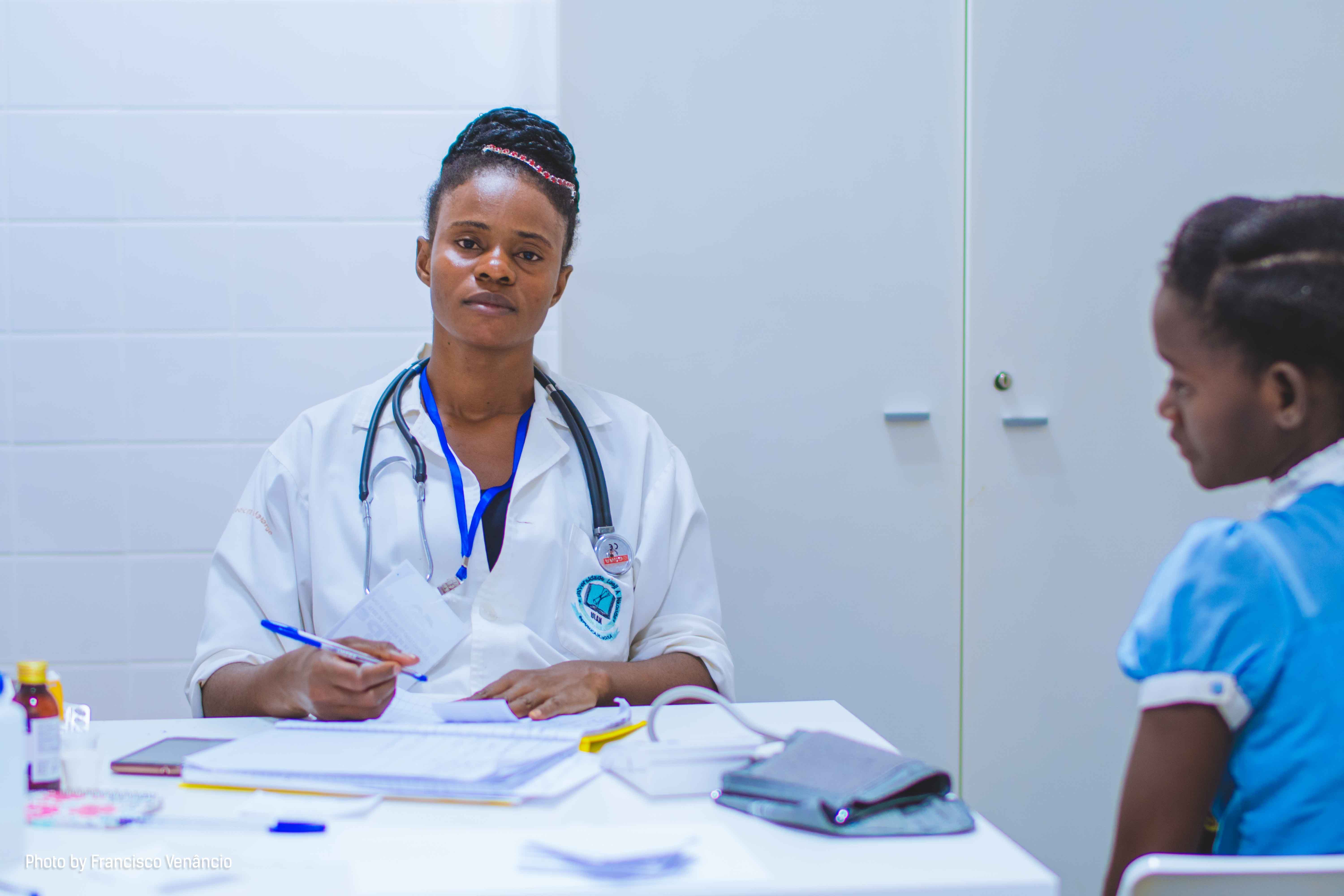 A doctor at her desk during a consultation with a young patient